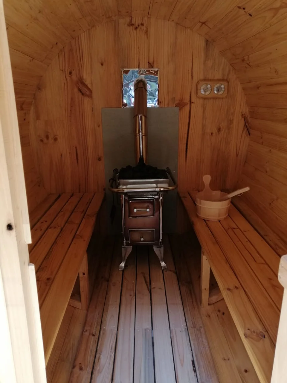 Calefactor a leña instalado entre bancas en un sauna de madera
